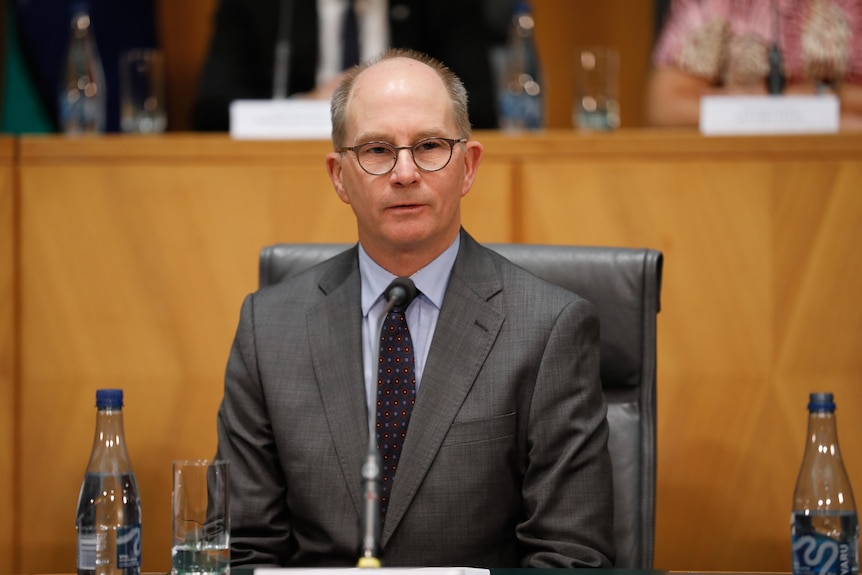 Chief Medical Officer Paul Kelly sitting in a committee room during a press conference