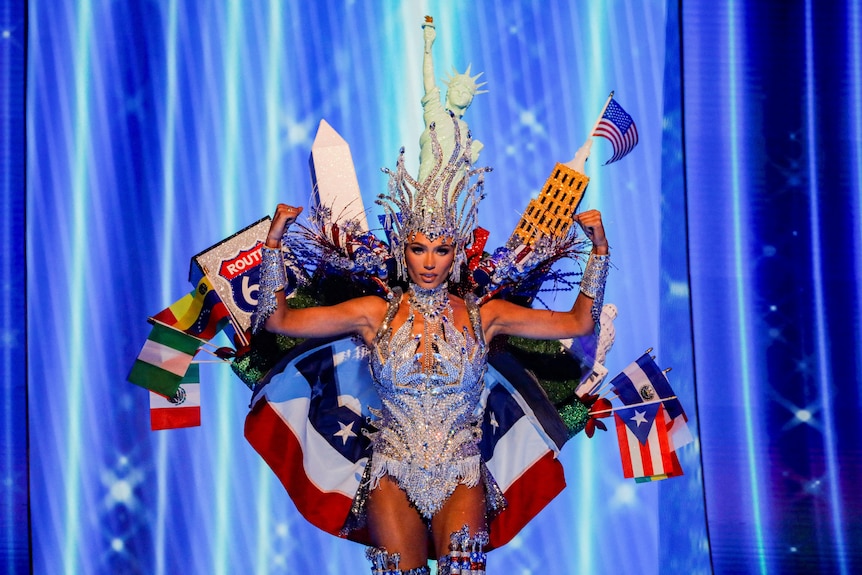 Noelia Voigt wearing a head dress with the State of Liberty on it, along with the Empire State building and flags