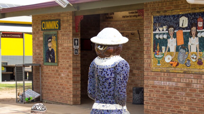 Public toilet block features a mosaic design on exterior walls that give appearance of a rail ticket booth.