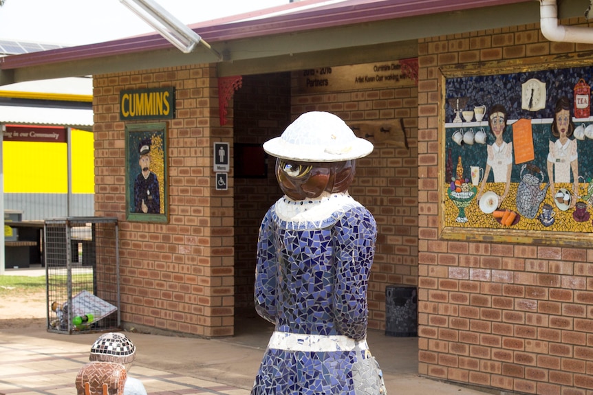 Public toilet block features a mosaic design on exterior walls that give appearance of a rail ticket booth.