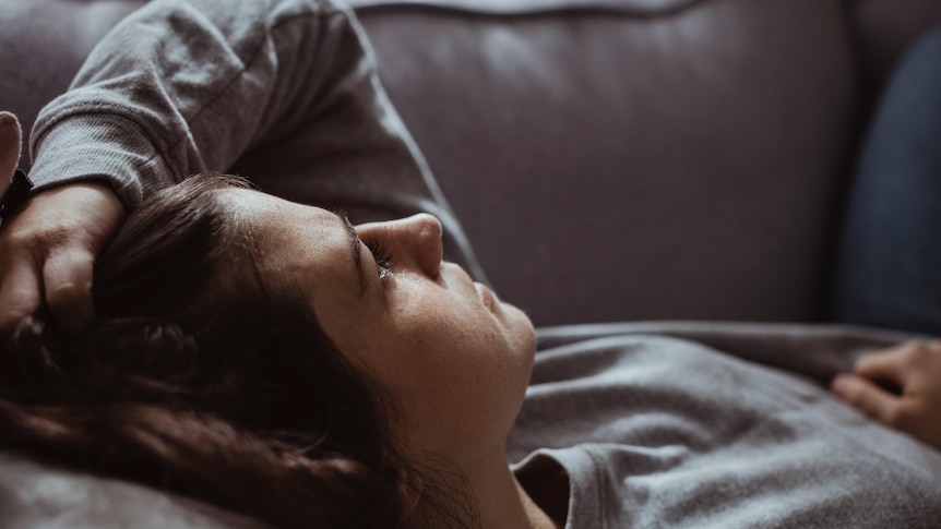 Close-up of sad woman lying on sofa at home.