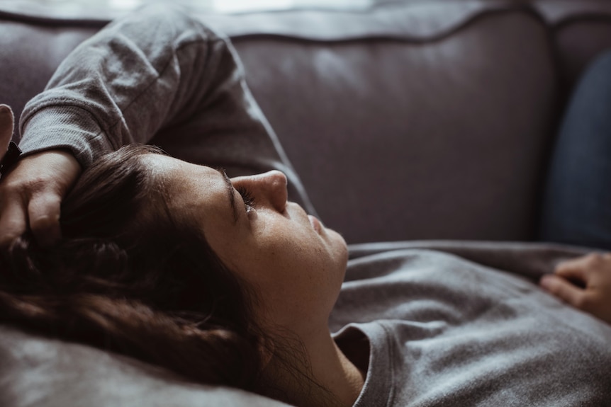 Close-up of sad woman lying on sofa at home.