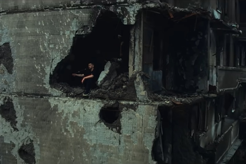 A member of Kalush Orchestra in a burnt-out building.  