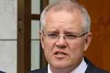 Mr Morrison is standing behind a lectern, holding up a copy of the bill. Attorney-General Christian Porter is behind him.