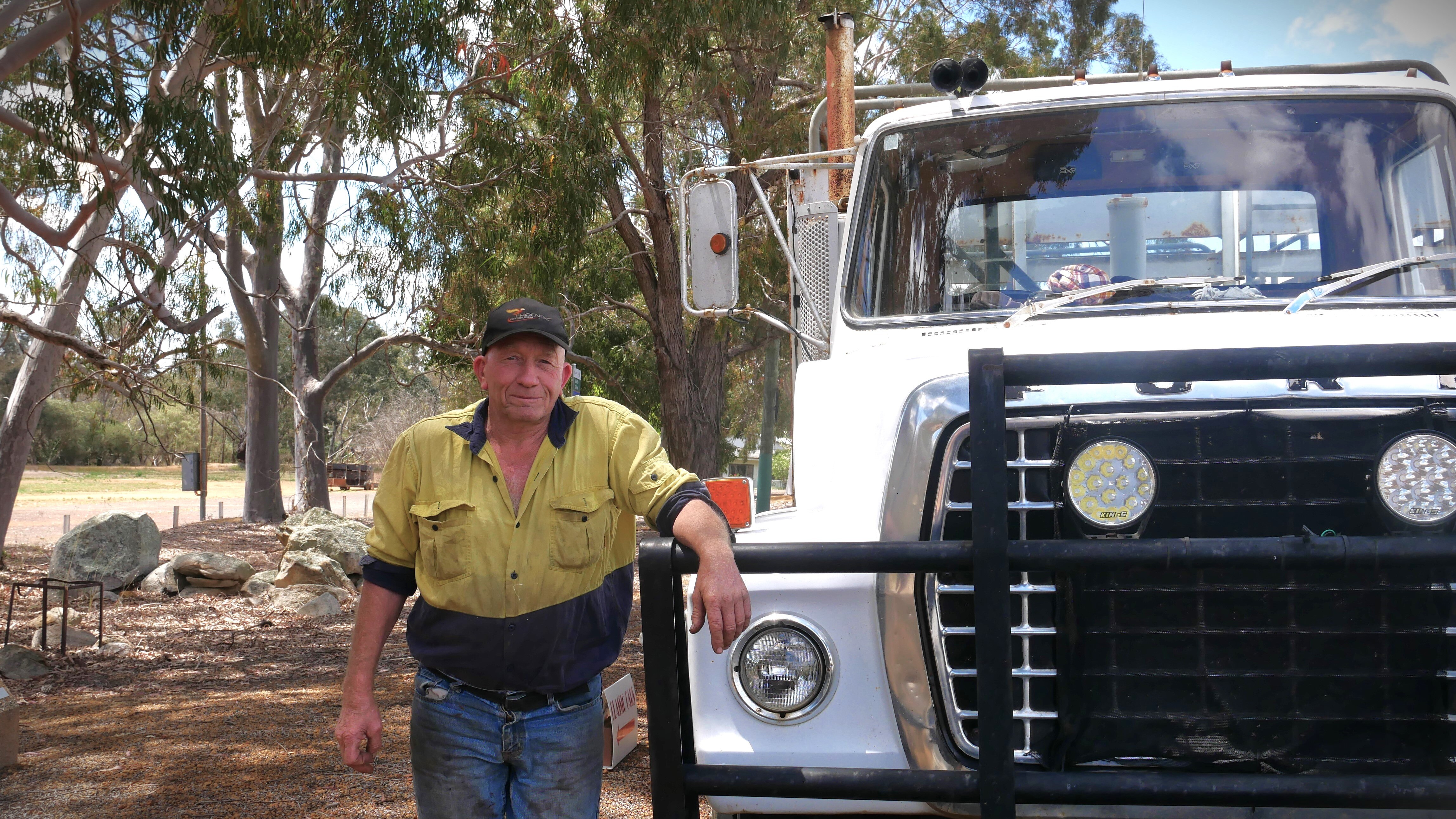 Farmer Neil Derrick leaning against the front of his white truck