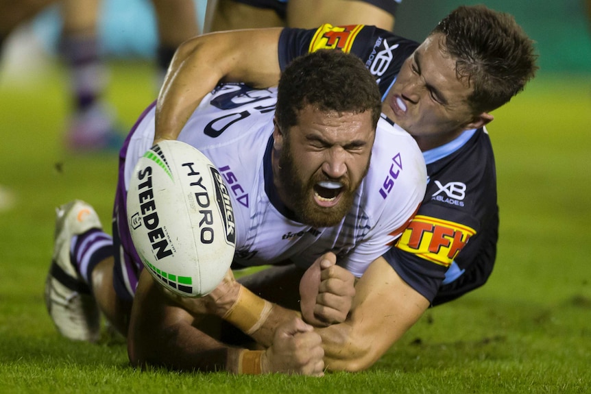 Kenny Bromich on the ground with his eyes closed as the ball is dropped in a tackle from a Sharks player.