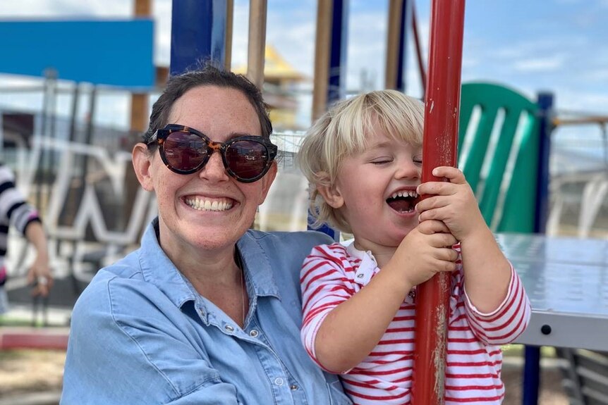 A woman in sunglasses with a toddler smiling
