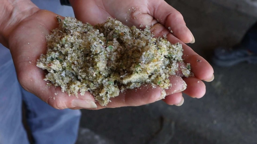 Hands hold a pile of glass sand