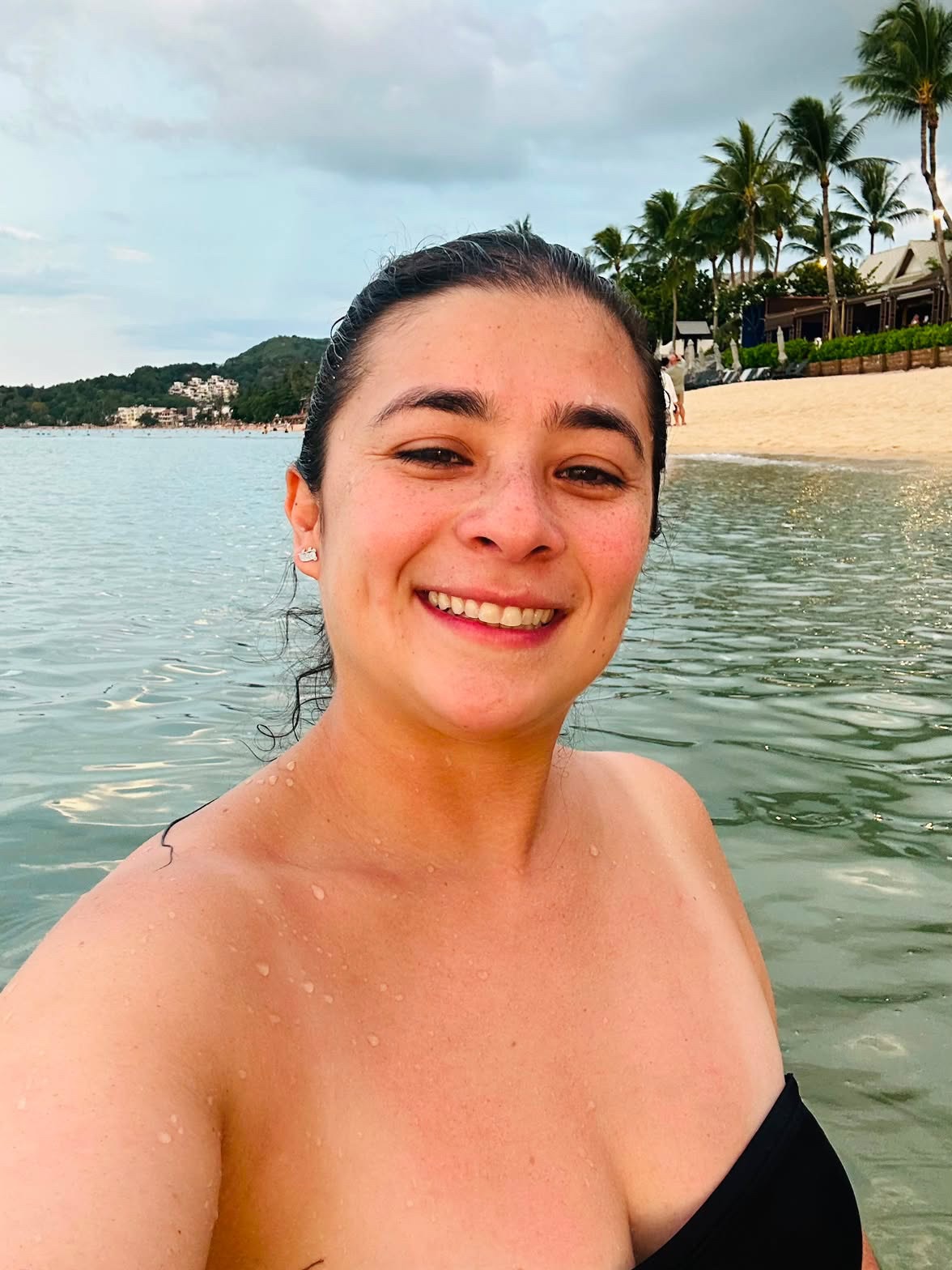 A relaxed, young woman stands in the water of a gorgeous Thailand beach.