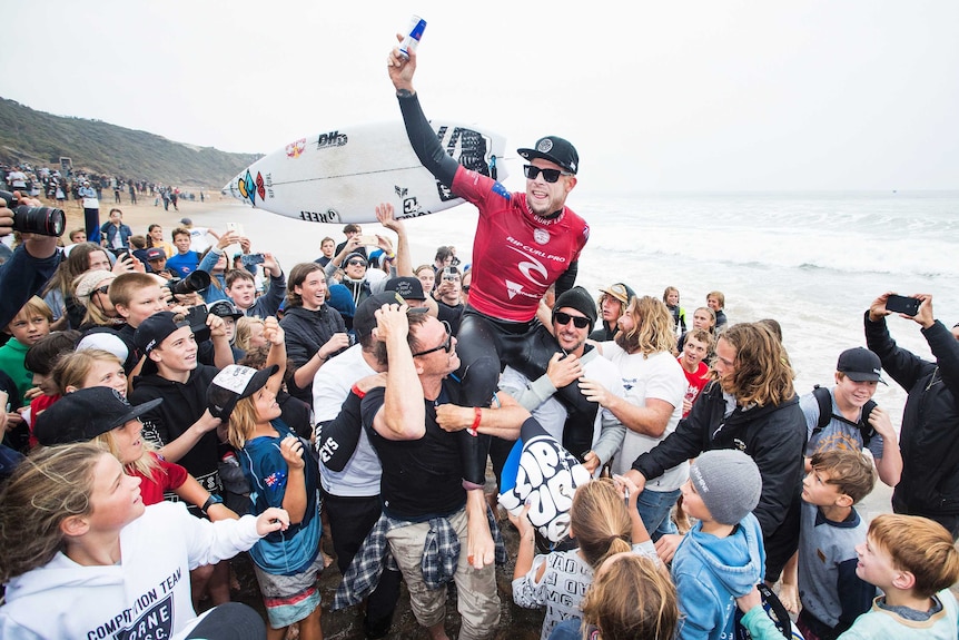Mick Fanning is chaired along the beach by members of the crowd at Bells Beach.