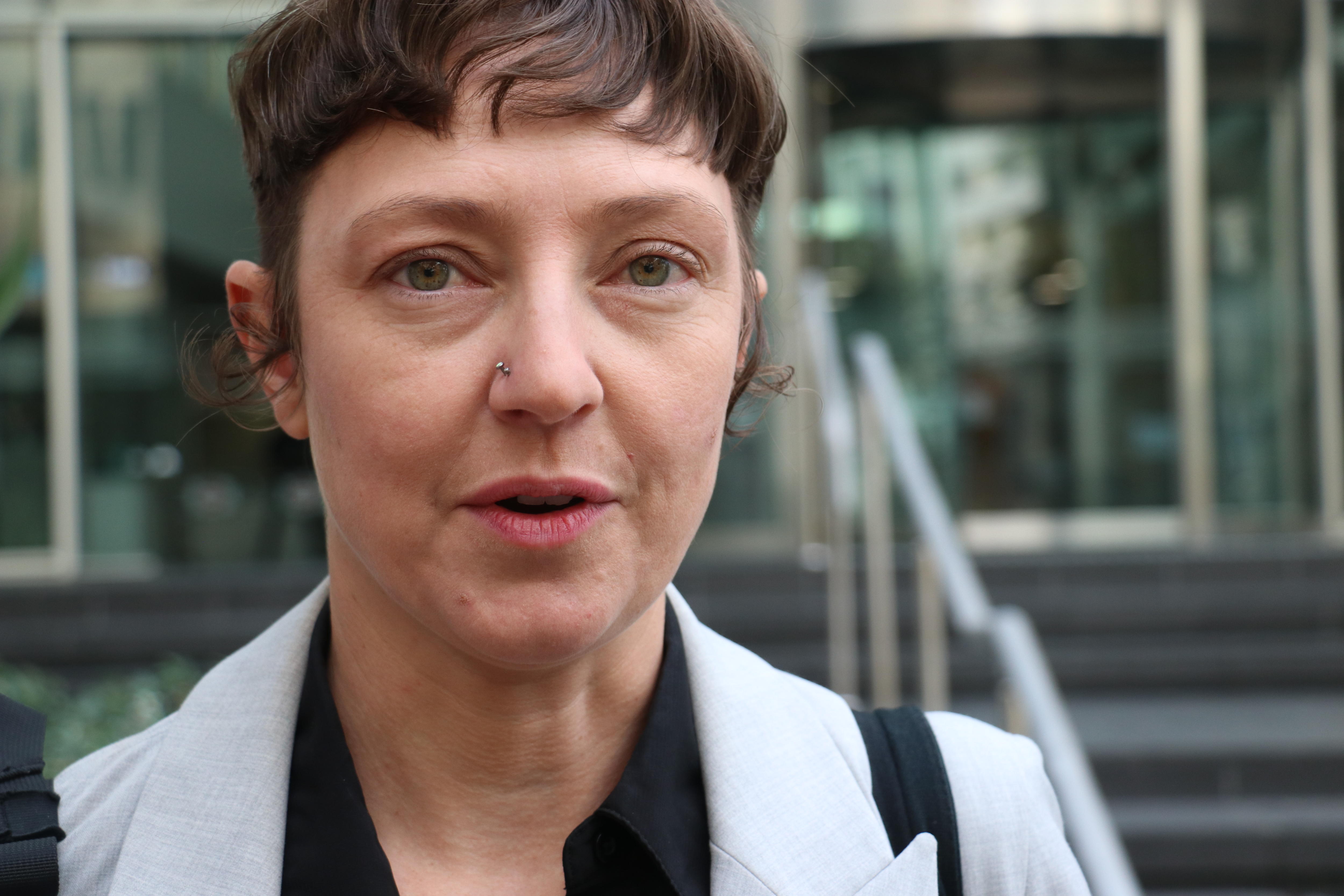 A woman with brown hair looks directly into the camera 