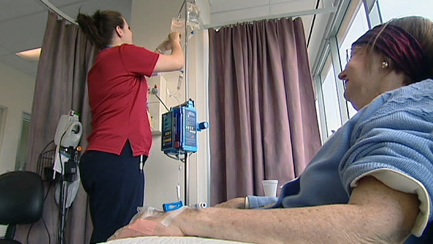 Nurse attends patient in hospital ward.