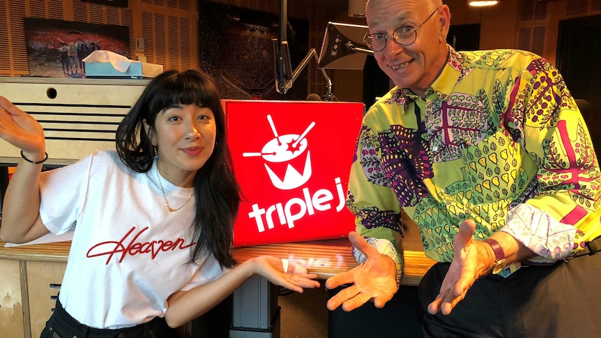 Dr Karl and Linda shrugging in front of the triple j logo