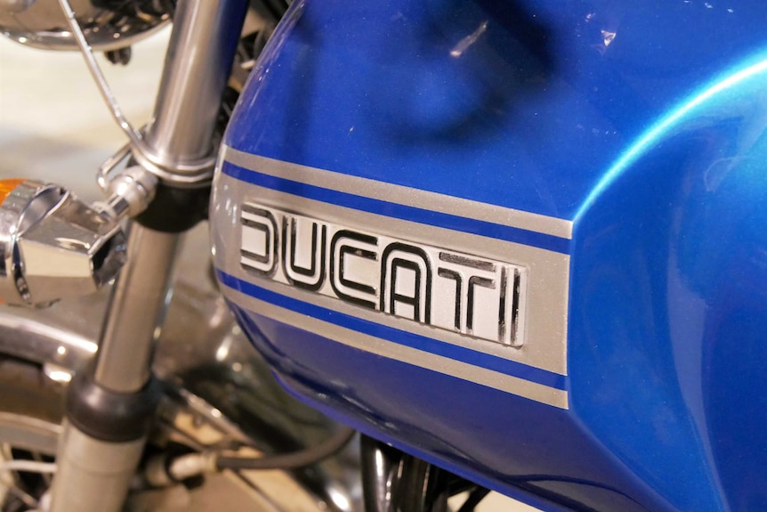 A close up shot of a Ducati motorcycle logo on a blue engine cover.
