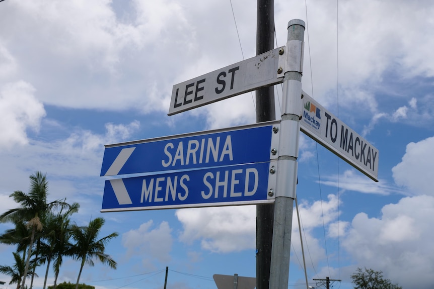 Street sign in front of blue sky and clouds. 