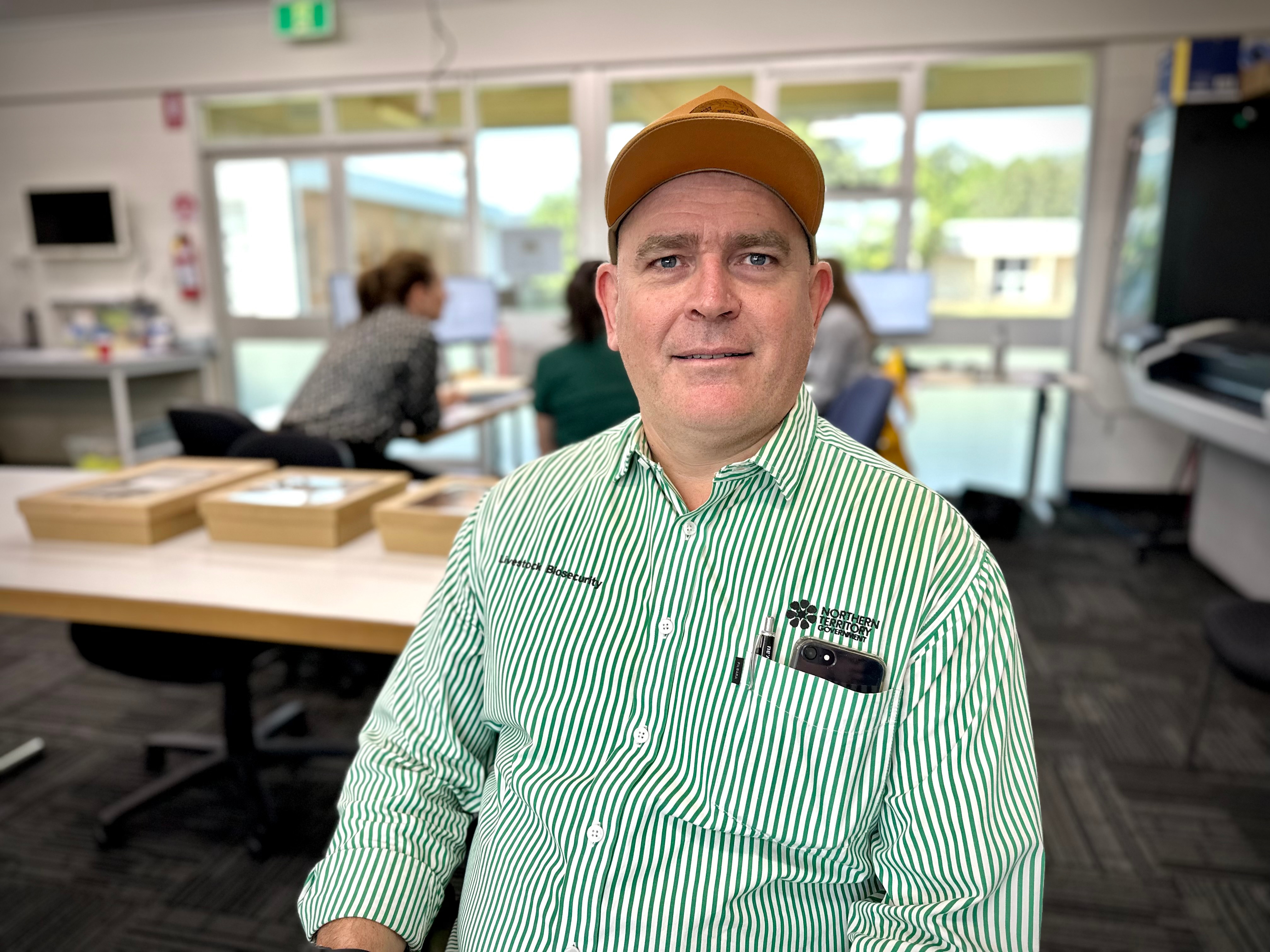 Um homem vestindo uma camisa listrada verde e branca e um boné laranja.
