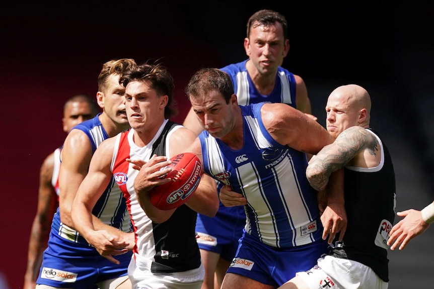 North Melbourne and St Kilda AFL players contest for the ball in a pack.