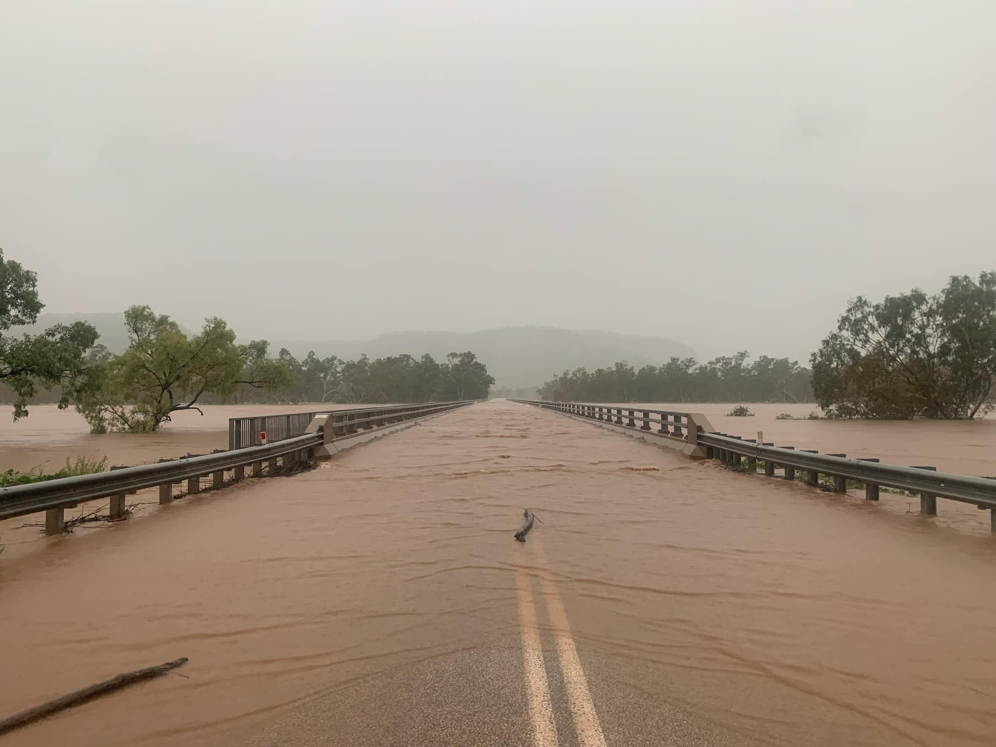 Flood water flows over the top of a bridge
