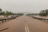 Flood water flows over the top of a bridge