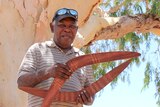 An Aboriginal man with boomerangs.