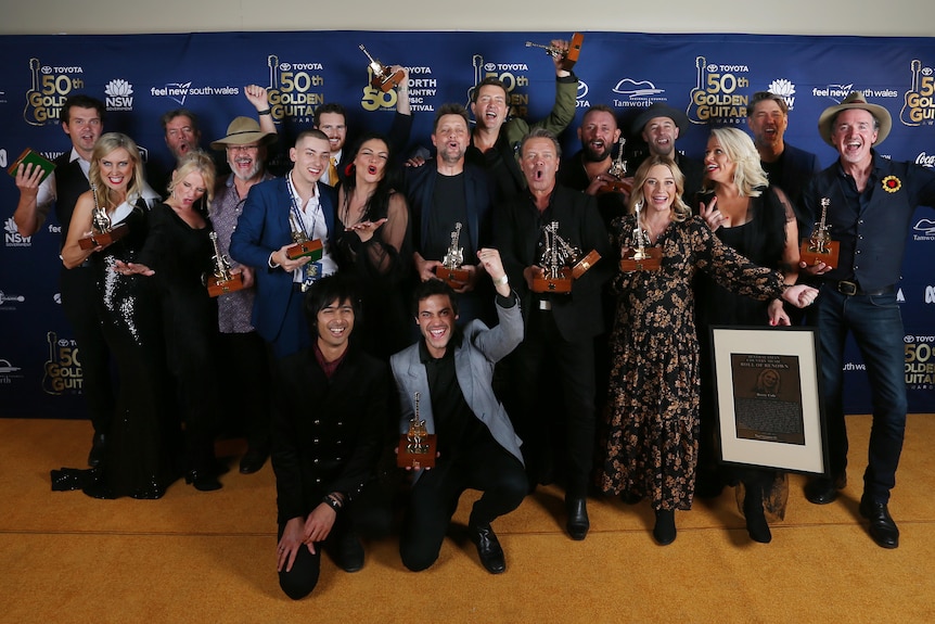 Um grupo de vencedores segura troféus e sorri no Golden Guitar Music Awards.