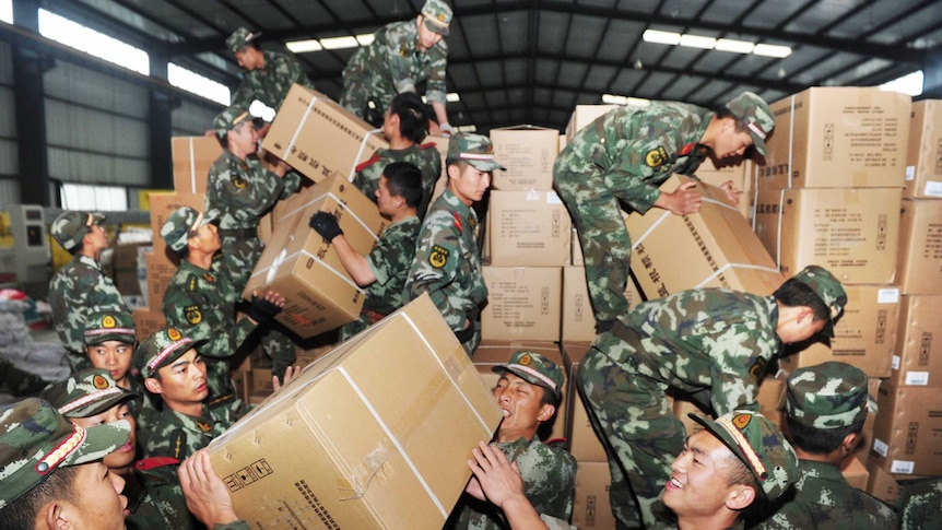 Chinese rescue workers unload medicine from pallets in a temporary settlement.