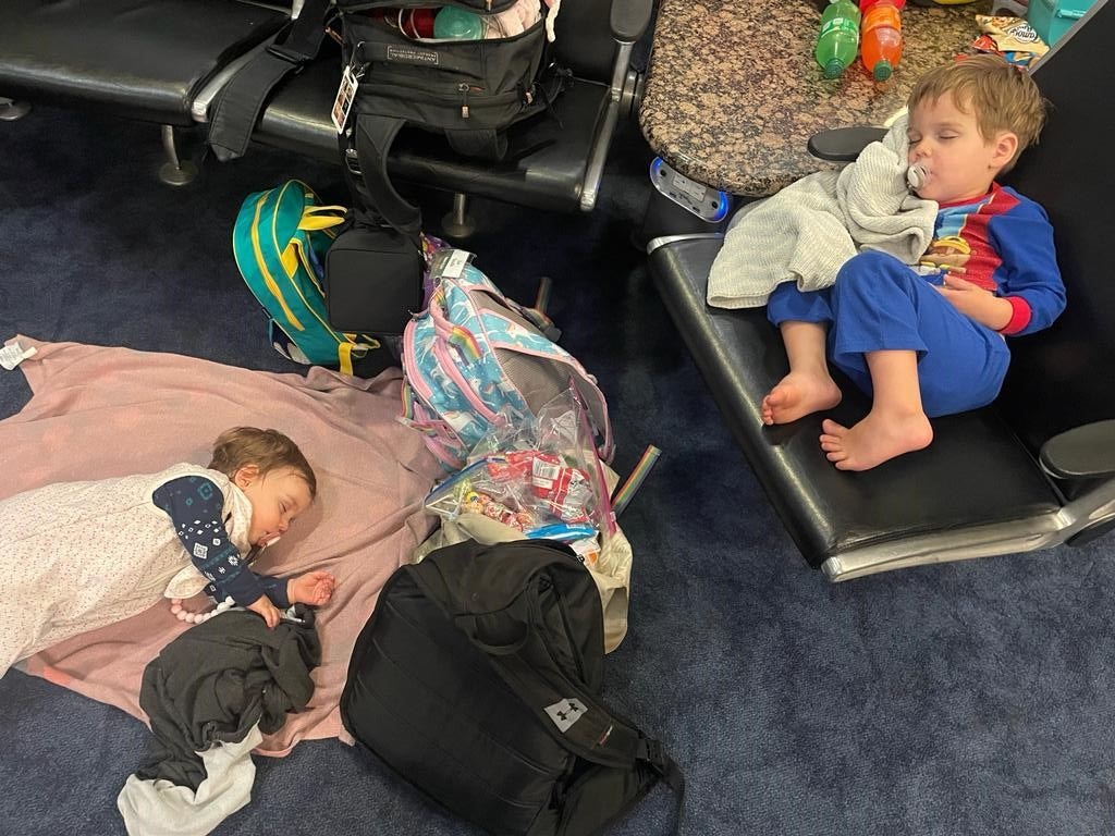Two children sleeping in an airport terminal.