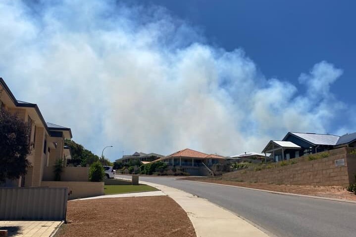 A picture of smoke billowing across a blue sky above a housing estate in outer Geraldton.