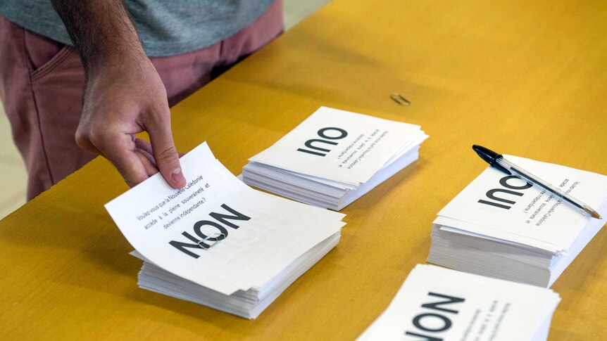 A man holds a ballot paper reading "non" in New Caledonia's independence referendum.