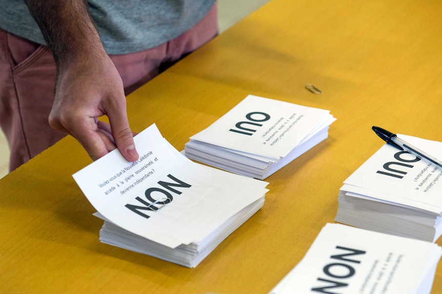 A man holds a ballot paper with the word "non" on it in the independence referendum in New Caledonia.