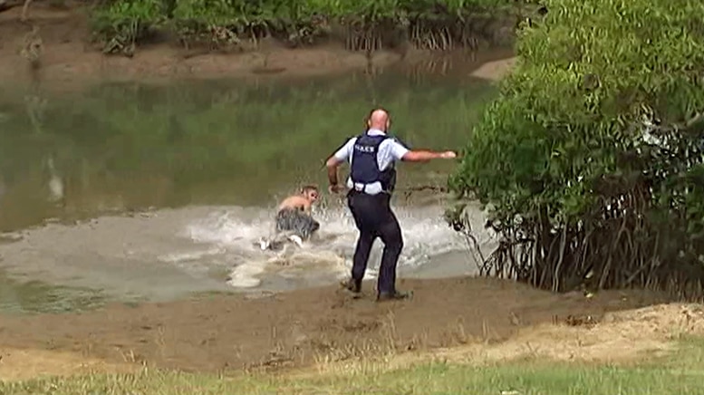 Queensland police officer stands on edge of Townsville creek.