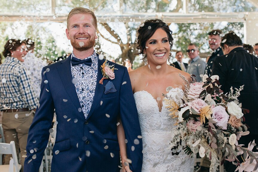 A man and a woman smiling through a shower of petals after being married