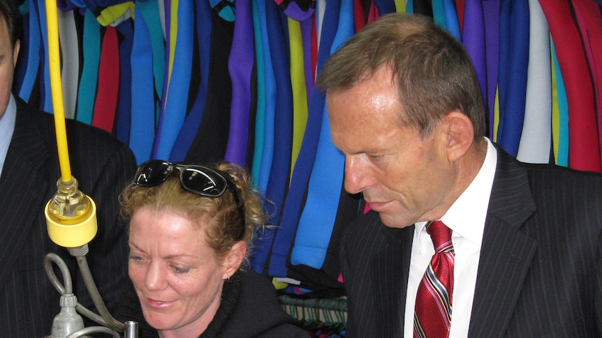 Federal Opposition leader Tony Abbott watches wetsuit making at a Hobart factory.