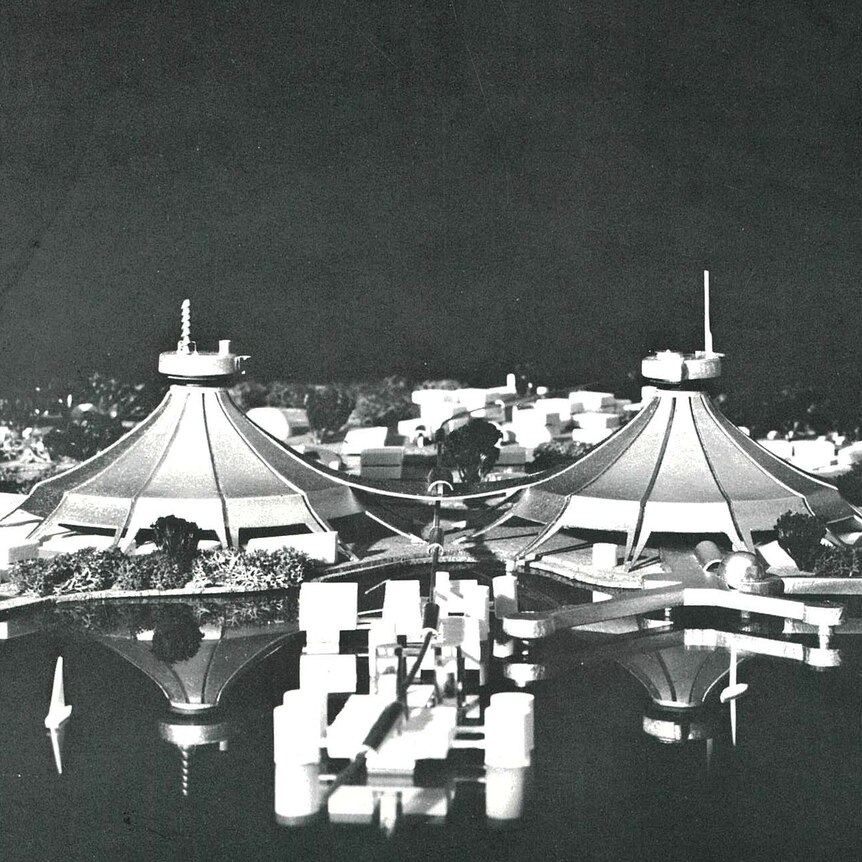A model of buildlings that have rooves shaped like circus tents beside a lake.