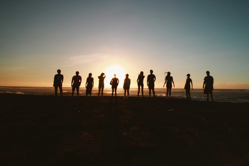 Silhouettes of people standing on a beach