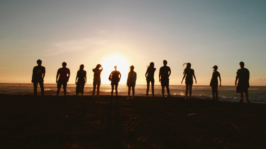 Silhouettes of people standing on a beach