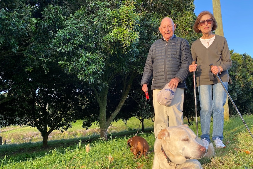 A older man and lady walking with their dogs