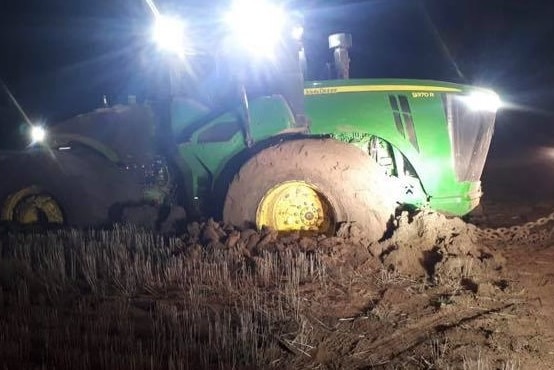 A green tractor stuck in mud