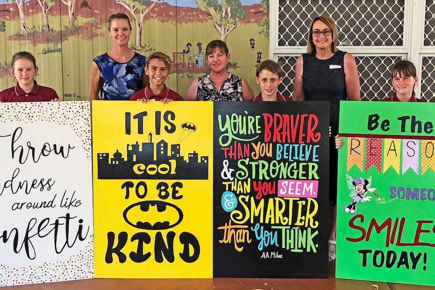 North Tom Price Primary School teachers and students holding colourful signs with positive messages.