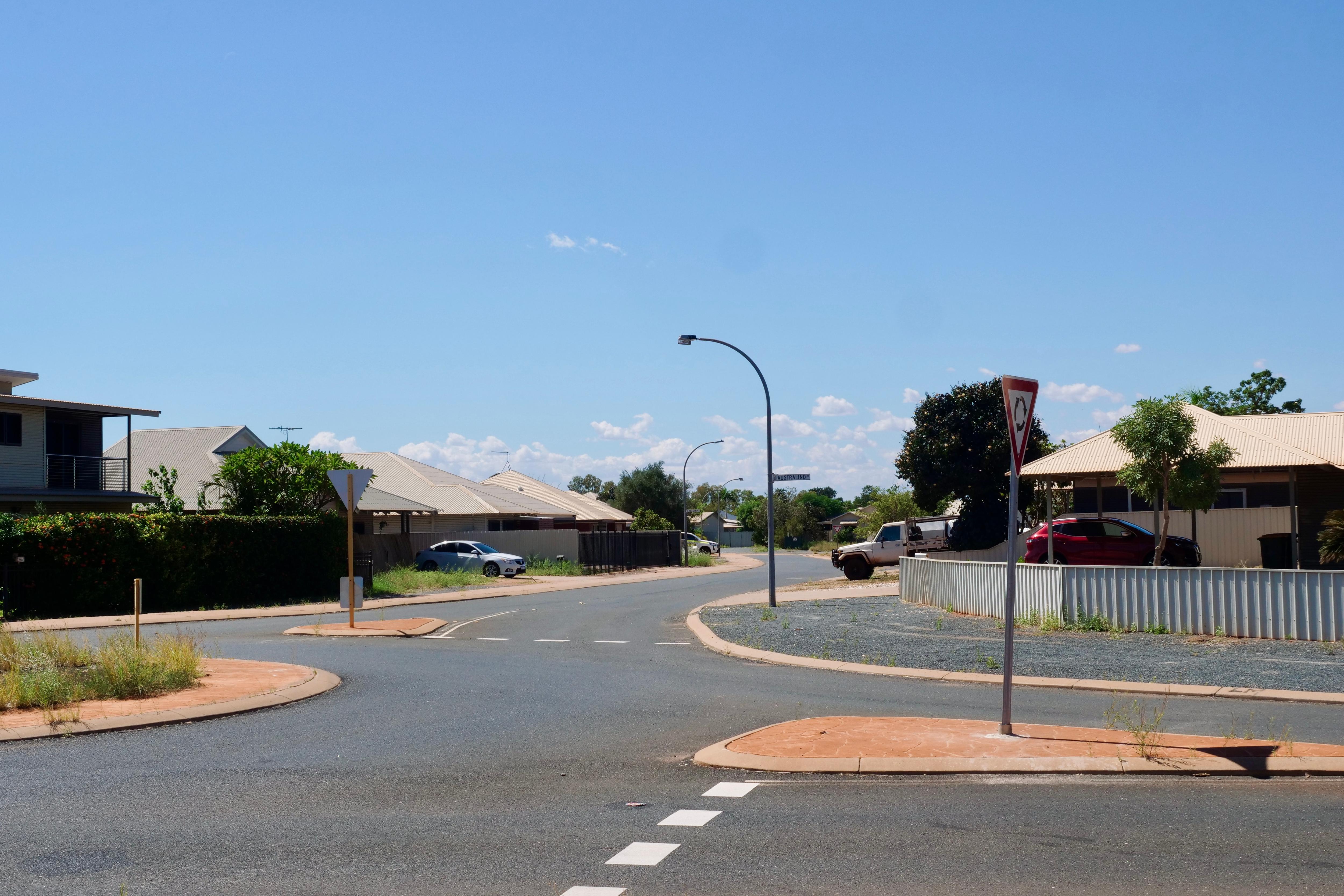 A roundabout in a suburban area beneath a clear sky.