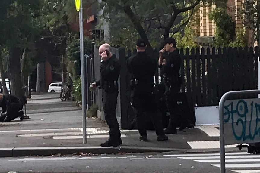 Police offices dressed in black standing on a corner in North Melbourne.
