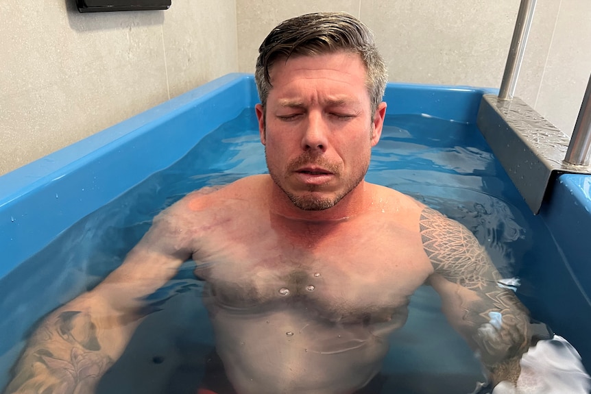 A man sits in icebath with his eyes closed