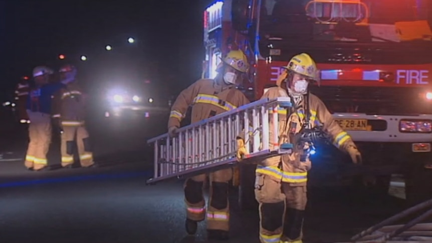 Firefighters use a ladder to access an apartment block fire at Ballina.