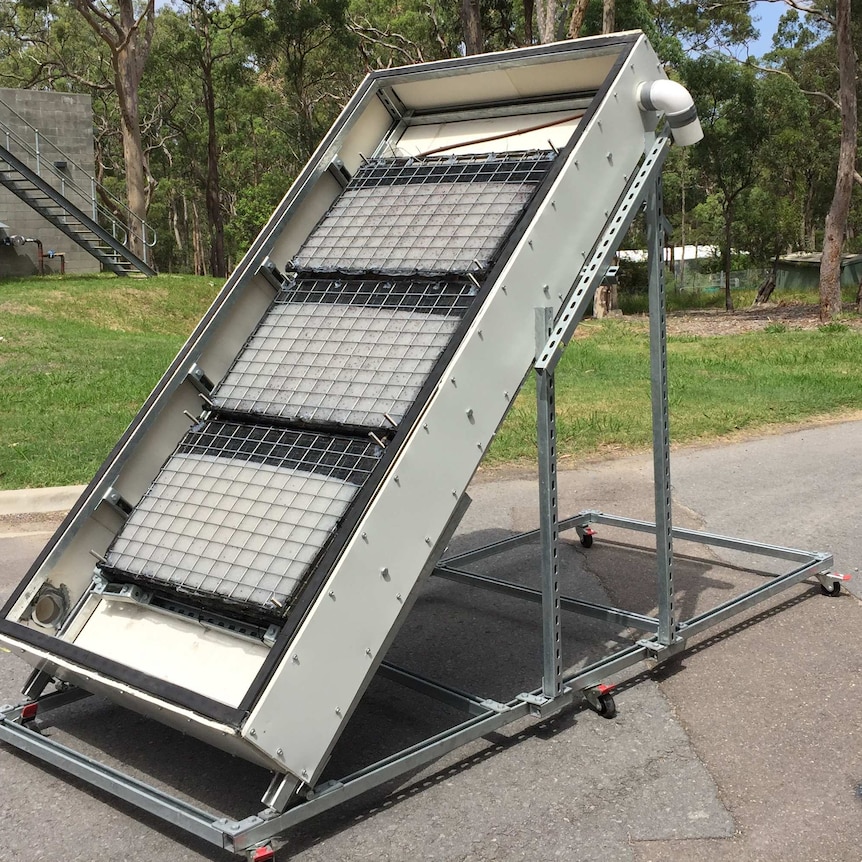 A large metal box sits on a tilt towards the sun outside.