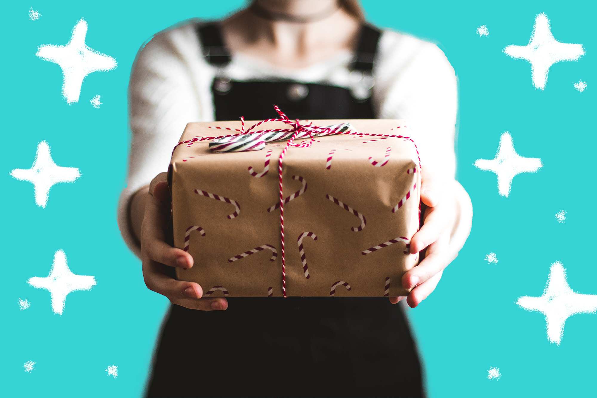 Woman holding a wrapped gift with a candy cane for a story about how to wrap gifts like an expert.