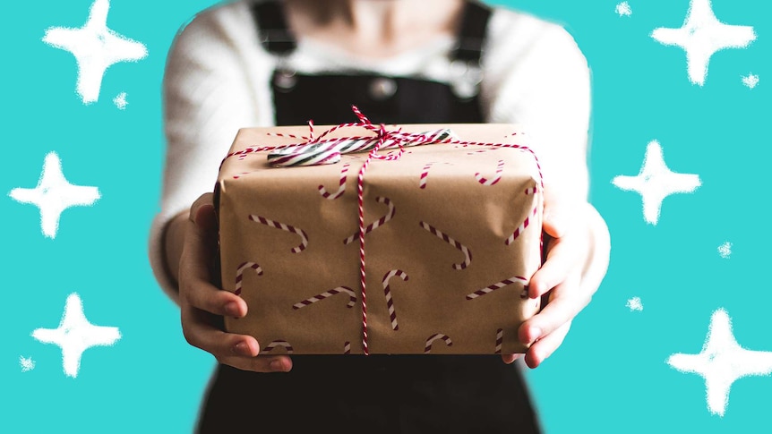 Woman holding a wrapped gift with a candy cane for a story about how to wrap gifts like an expert.