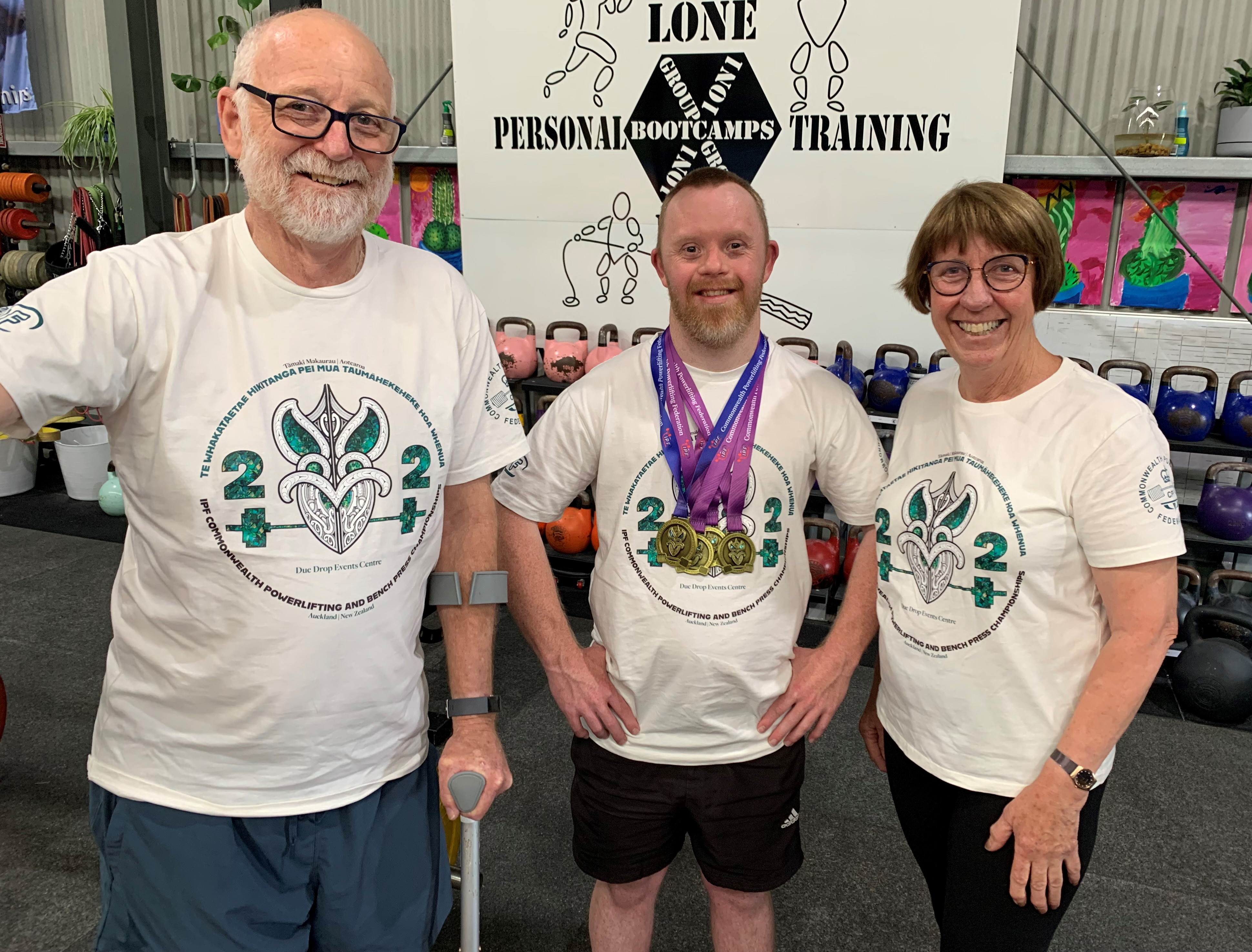 Phillip, Jack and Merril  Carroll smile and stand together in a gym.