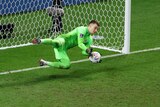Goal keeper saves a ball in front of the net. 