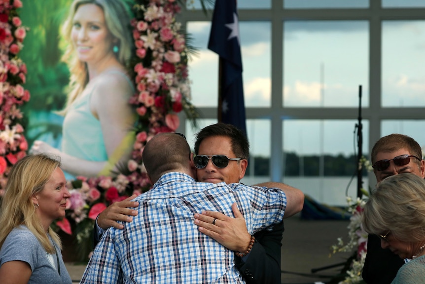 Don Damond hugs a supporter in front of a photo of Justine Damond.