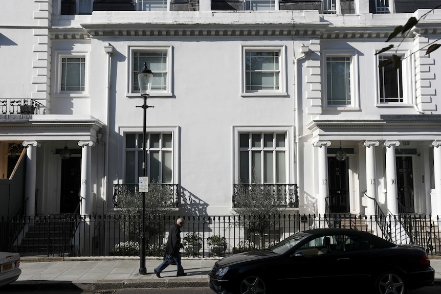 A white attached home with large windows and a neat front yard in a London street.